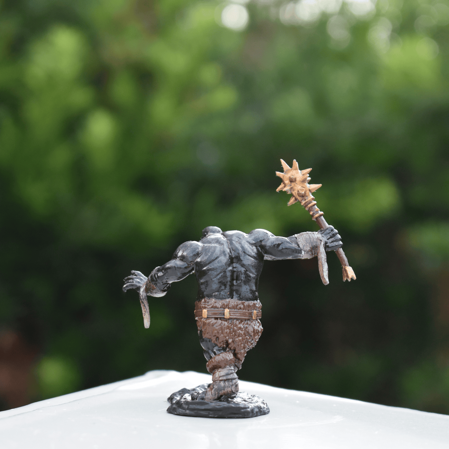 Back view of the Black Fire Undead Orc DnD miniature showing detailed muscle shading, fur clothing, and raised spiked weapon.