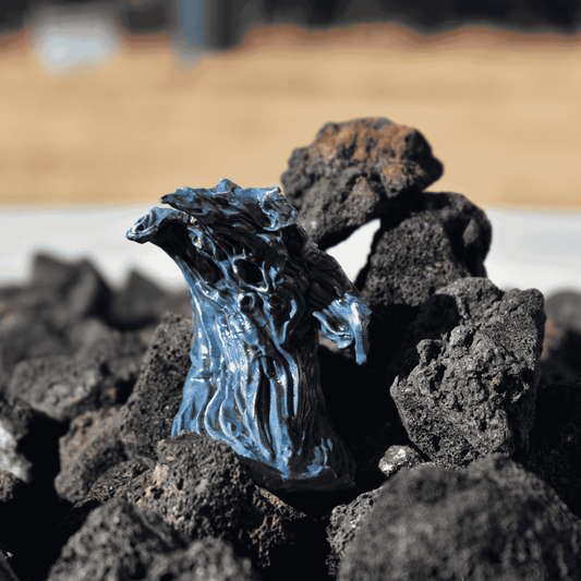 Dramatic side view of a Water Elemental miniature with fluid, hand-painted textures in blue and silver, resting on lava rocks.