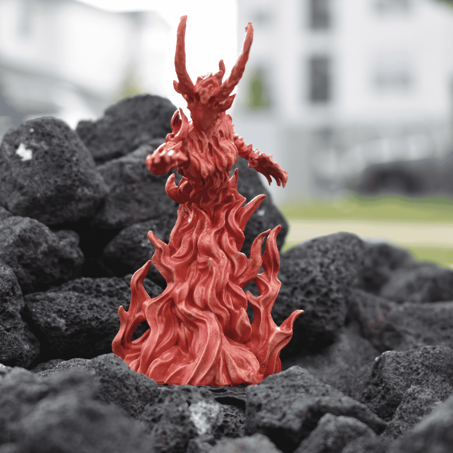 Hand-painted Fire Queen miniature rising from sculpted flames, posed dramatically atop black volcanic rock terrain.