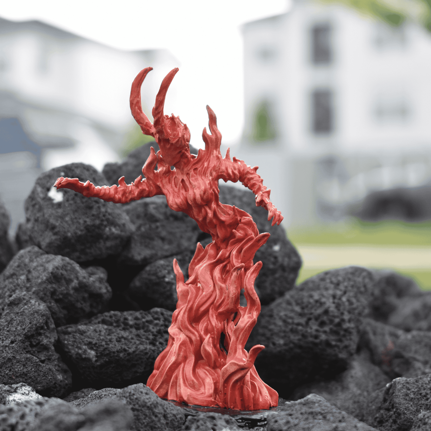Red and orange fire elemental queen figure with horned crown and flame-swept body, posed among dark rocks.