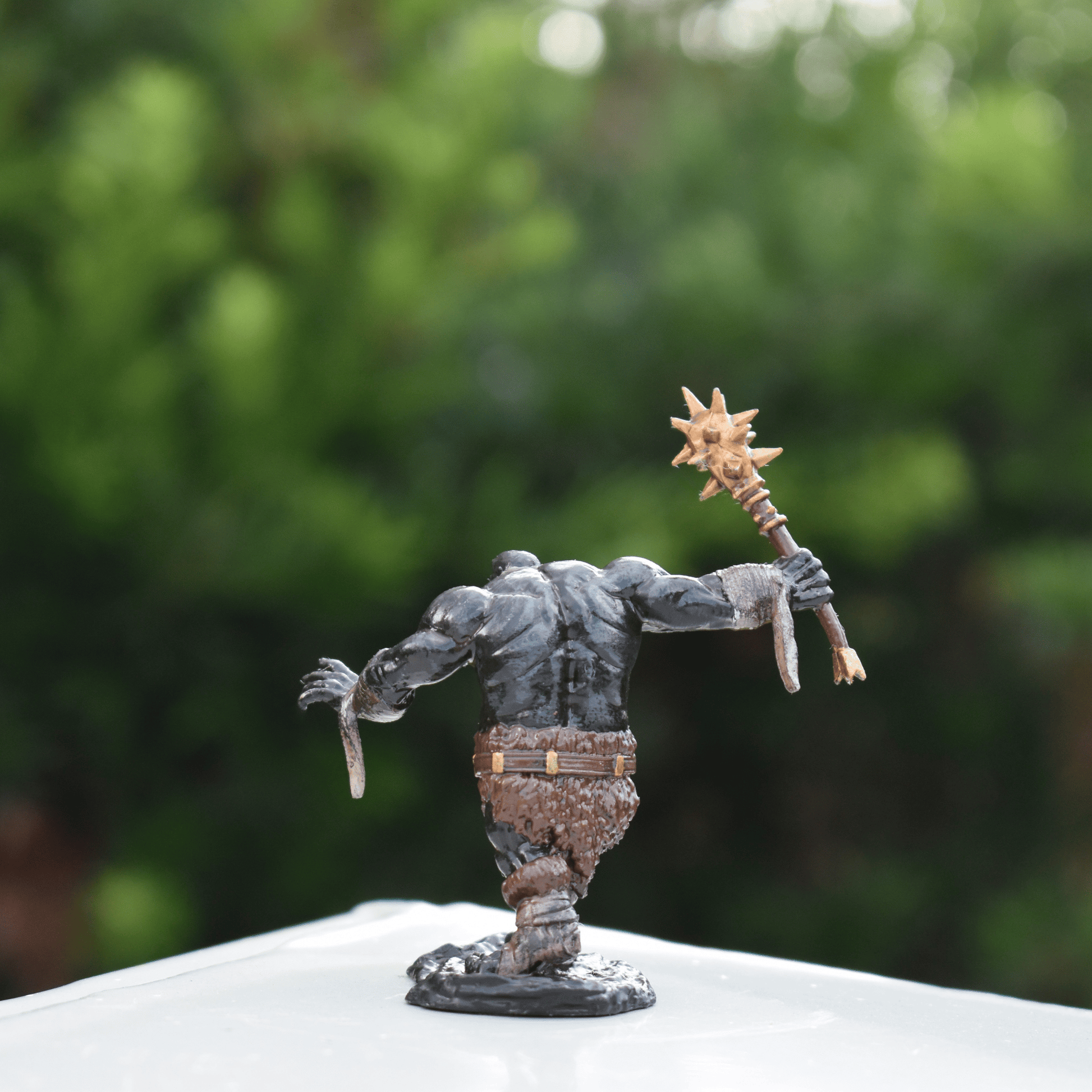 Back view of the Black Fire Undead Orc DnD miniature showing detailed muscle shading, fur clothing, and raised spiked weapon.