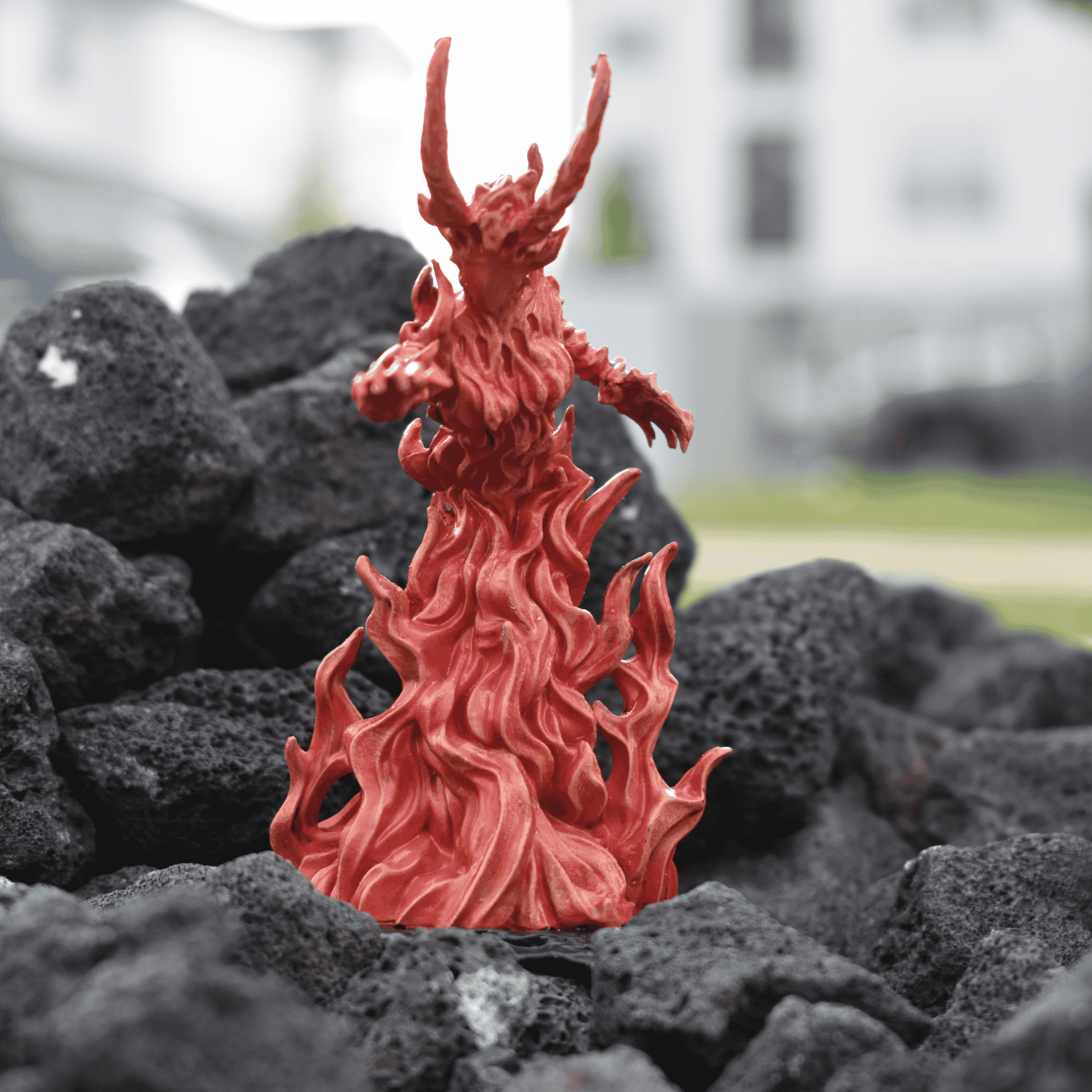 Hand-painted Fire Queen miniature rising from sculpted flames, posed dramatically atop black volcanic rock terrain.