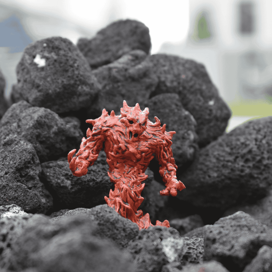 A hand-painted fire elemental miniature in ember-red and black tones, posed menacingly among dark volcanic rocks. The figure appears to emerge from the rocky terrain with arms raised, ready for battle.