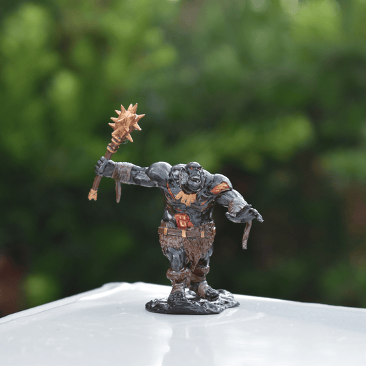 Front view of the Black Fire Undead Orc miniature, hand-painted with red and gold accents, displayed on a white surface with greenery background.