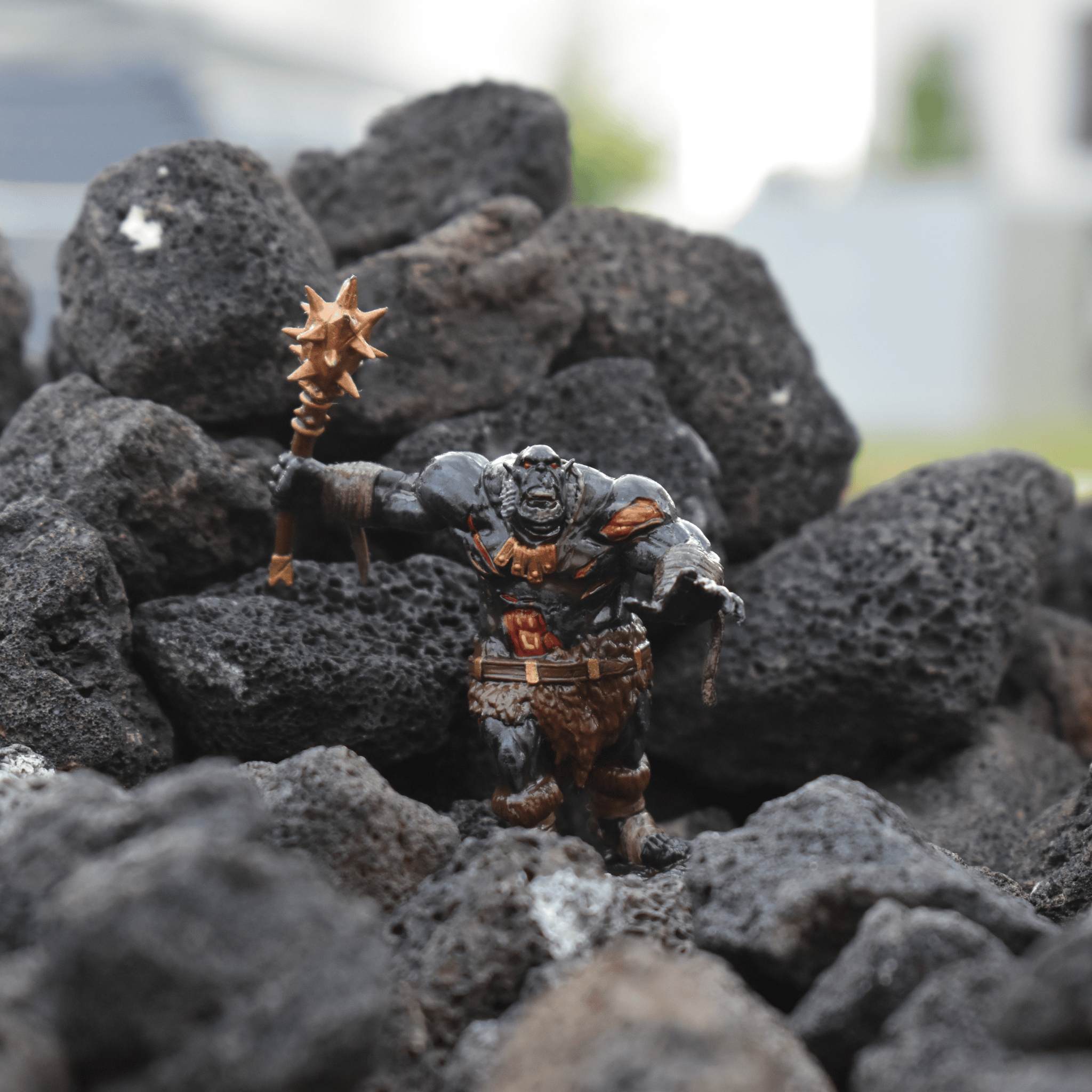 Hand-painted Black Fire Undead Orc miniature posed in a lava rock terrain, holding a spiked mace with an aggressive stance.